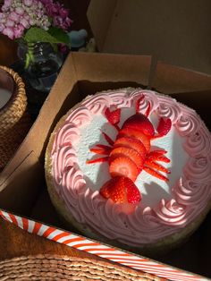 there is a cake with strawberries on it in the box next to some candy canes