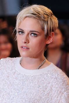 a woman with blonde hair wearing a white sweater and diamond necklace on the red carpet