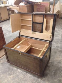 an open wooden box sitting on top of a floor next to other boxes and drawers