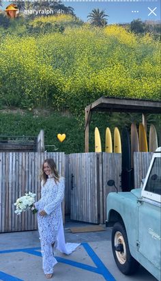 the pregnant woman is standing in front of her truck and holding a bouquet of flowers