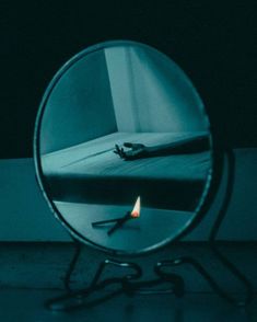 a mirror with a reflection of a bed in it and a lit candle on the floor