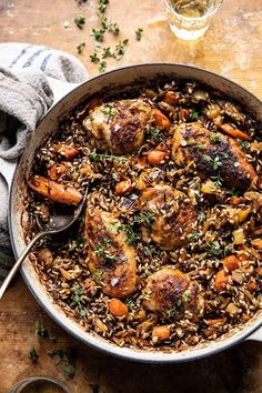 chicken and wild rice in a skillet on a wooden table with a glass of wine