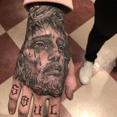 a person with a tattoo on their hand and the word jesus painted on his palm