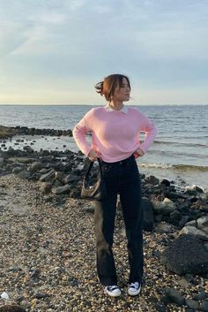 a woman standing on top of a rocky beach