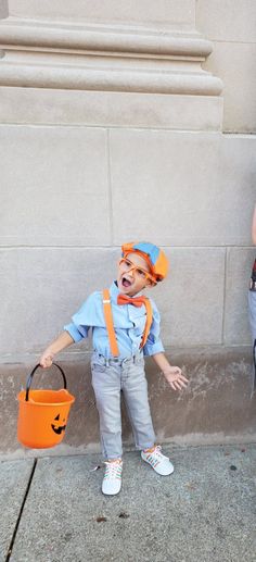 two children dressed up as clowns and one is holding a bucket with a pumpkin on it