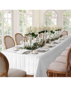 a long table is set with white flowers and place settings for the guests to sit at