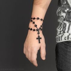 a person wearing a rosary bracelet with a cross on it's wrist and black beads