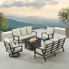 an outdoor fire pit with four chairs and a coffee table on top of the patio