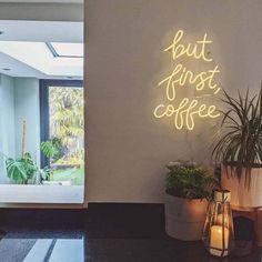 there is a neon sign that says but first coffee next to a potted plant