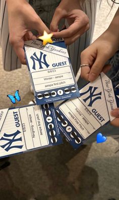 two people holding up tickets with the new york yankees logo on them and butterflies flying around