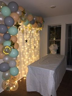 balloons and stars are hanging from the ceiling above a table with a white tablecloth on it