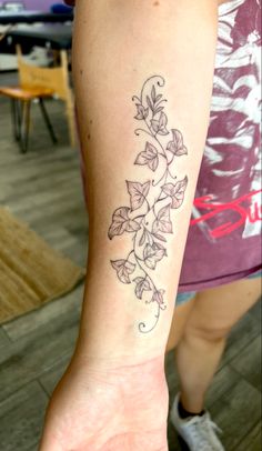 a woman's arm with a tattoo on it that has vines growing out of it