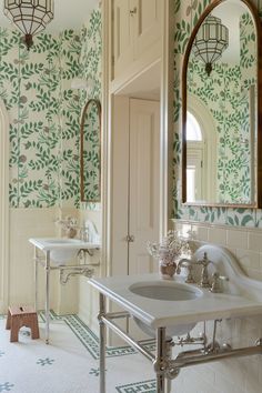 a bathroom with green and white wallpaper on the walls, two sinks and mirrors