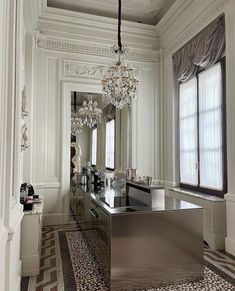 an elegant bathroom with chandelier, mirror and tiled flooring in the room