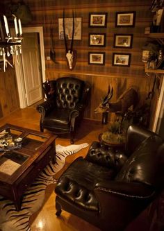 a living room filled with black leather chairs and zebra print rug on top of a hard wood floor