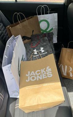 bags in the back seat of a car with paper shopping bags sitting on top of them