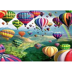 many hot air balloons flying in the sky with rainbows and mountains behind them,