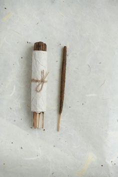 two sticks tied up next to each other on top of a white surface with brown paper