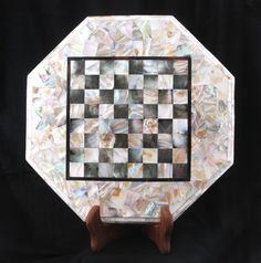 a white and black checkerboard plate with wooden legs on a black background in the shape of a hexagonal object