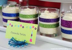 there are several small desserts in glass cups on the counter with a name tag