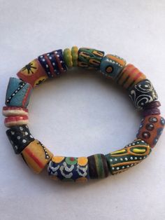 "This colorful bracelet is handmade from recycled glass, formed into beads known as Krobo beads, hand painted, and fired in a kiln in Ghana, West Africa.  The bracelet is 6\" and is strung on 2mm white elastic cord. It features hand-painted African designed glass beads. Other sizes may be ordered as well as earrings and other jewelry. Just contact us.  All proceeds from the sale of this jewelry go to our non-profit organization Mawuvio's Outreach Programme, which is providing free education and care for orphaned and disadvantaged children in Ghana. The money is used to support a 6 classroom and 2 dormitory school that provides over 200 children with the tool they need to succeed - Education. Students & staff at Mawuvio's Outreach Programme string the beads themselves to create handmade bra Artisan Wooden Beads Stretch Bracelet, Artisan Multicolor Beaded Stretch Bracelet, Multicolor Hand Painted Round Bead Jewelry, Artisan Multicolor Wooden Beaded Bracelets, Handmade Multicolor Recycled Glass Beads, Artisan Hand-strung Stretch Bracelet For Festivals, Adjustable Recycled Glass Beads With Large Beads, Artisan Multicolor Round Beads Stretch Bracelet, Artisan Multicolor Stretch Bracelet With Round Beads