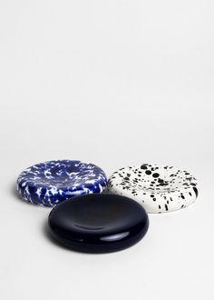 three black, white and blue plates sitting next to each other on a white surface