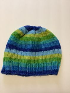 This soft, hand-knit hat/beanie will comfortably fit most adults and teens. It's made using a fun, self-striping and soft yarn that will be warm and comfortable. Hand-knit (NOT loomed or machine-knit) using a high-quality, super-soft striping yarn. You'll reach for this hat again and again on your way out the door, so the easy-care yarn means you can machine wash and dry your hat whenever you want. Adjustable Striped Winter Hat, Striped Winter Hats One Size Fits Most, Striped Beanie Hat, One Size Fits Most, Striped Beanie Hat One Size, Winter Striped Hats One Size Fits Most, Blue Knit Beanie Hat, Casual Striped Cap, Blue Knit Beanie, Blue Knitted Beanie One Size