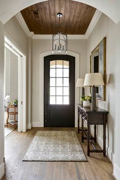 an entryway with a black door and white walls, wood floors and a rug on the floor