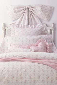 a white bed topped with pink pillows and blankets