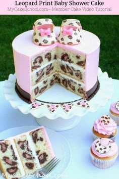 a pink and brown leopard print baby shower cake with cupcakes on the side