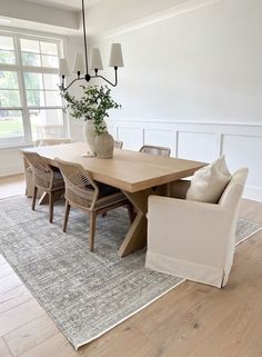 a dining room table with chairs and a rug on the floor in front of it