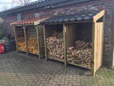 several stacks of firewood sit in front of a brick building with a red tin roof