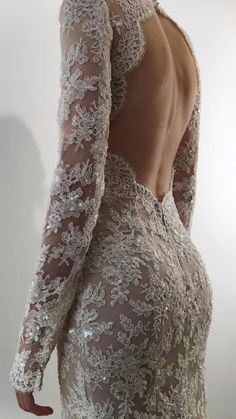 the back of a woman's wedding dress with long sleeves and lace on it