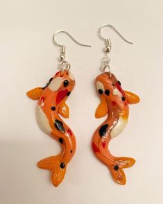 two orange and white koi fish earrings with silver earwires on a white surface