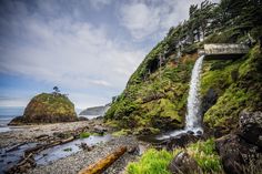 there is a waterfall in the middle of some rocks and trees on the side of the hill