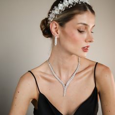 a woman in a black dress wearing a tiara and necklace with flowers on it