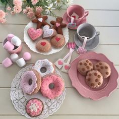 there are many different types of cookies on the table with pink and white plates next to them