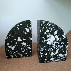 two black and white marble bookends sitting on top of a brown cloth covered table