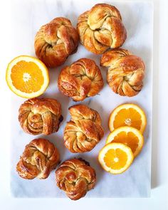 oranges and croissants are arranged on a white surface with one cut in half