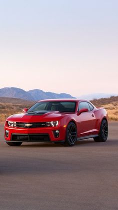 two chevrolet camaros are driving down the road