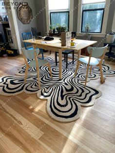 a dining room table with chairs and rugs on the floor in front of two windows