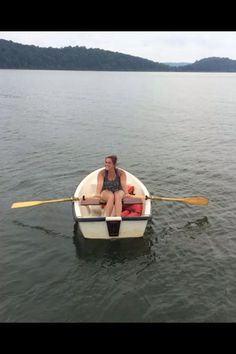 a woman sitting in a row boat on the water