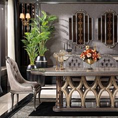 an elegant dining table with two chairs and a vase filled with flowers next to it