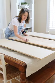 a woman sanding wood on top of a table