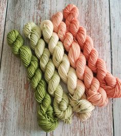 several skeins of yarn laid out on a white wooden surface, including orange and green