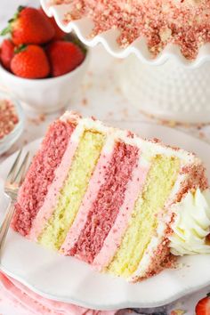 a slice of cake on a plate with strawberries in the background