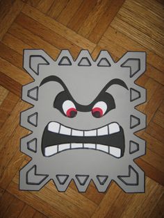 a paper cut out of a monster face on a wooden floor with red eyes and teeth