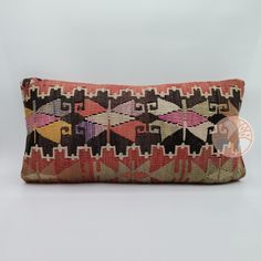 an old, colorful pillow is sitting on a white surface with a black and red design