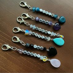 several different types of bead and charm bracelets on a wooden table with scissors