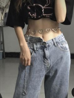 a woman wearing jeans and a crop top is talking on her cell phone while standing in front of a mirror